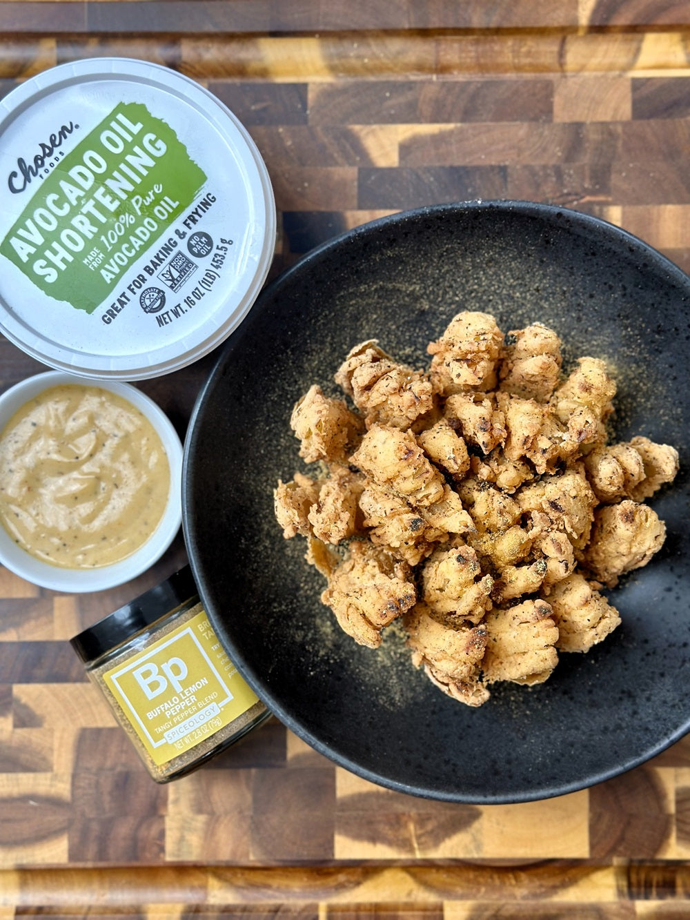 Finished Buffalo Lemon Pepper Bloomin’ Onion with a jar of Spiceology Buffalo Lemon Pepper and Chosen Foods' Shortening  