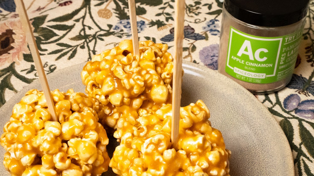 Caramel Apple Cinnamon Popcorn Balls on a plate next to a Spiceology Apple Cinnamon blend jar