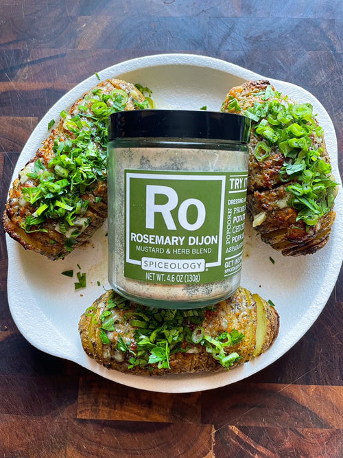 Jar of Spiceology Rosemary Dijon surrounded by hasselback potatoes on a plate