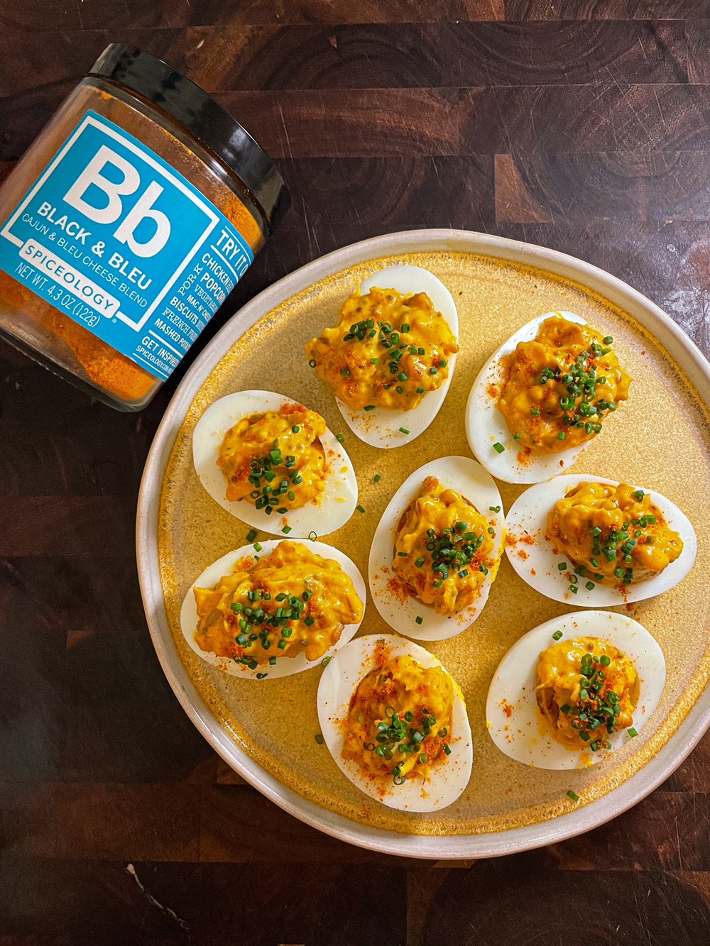 Plate of Black & Bleu Deviled Eggs next to a jar of Spipceology Black & Bleu spice blend