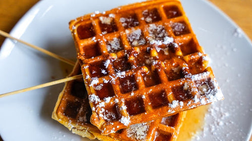 Plated Chicken & Waffle on a Stick topped with powdered sugar