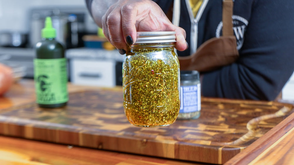 Chef Christian Gill holding and showing Spiceology Greek Freak infused olive oil in mason jar 