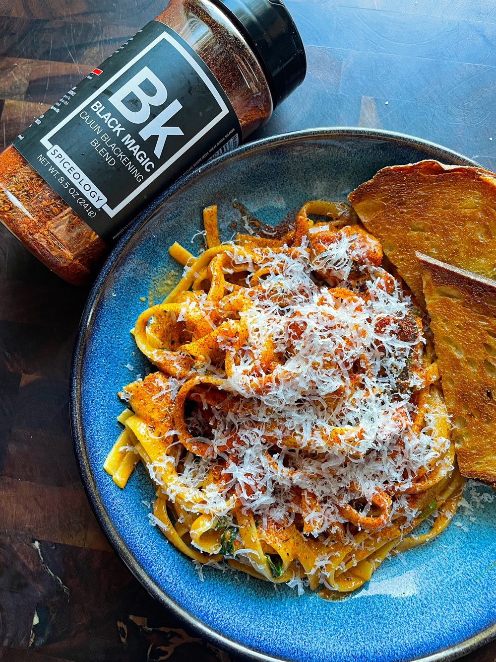 Plated Chicken Alfredo Pasta next to a Spiceology Black Magic jar