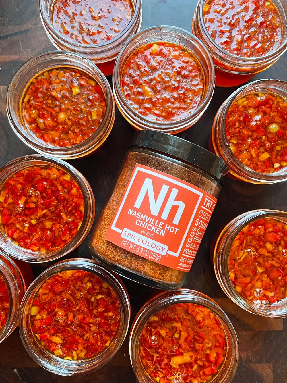 Jar of Spiceology Nashville Hot Chicken blend surrounded by jars of hot pepper jelly