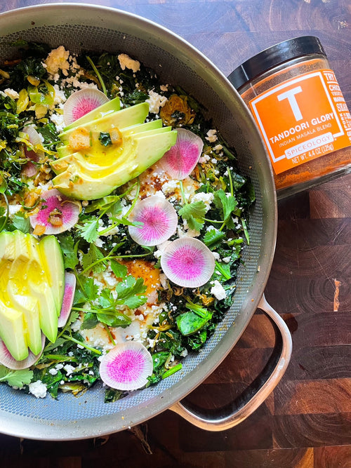 Green Shakshuka in a pan and topped with radishes, avocado and cilantro next to a Spiceology Tandoori Glory jar