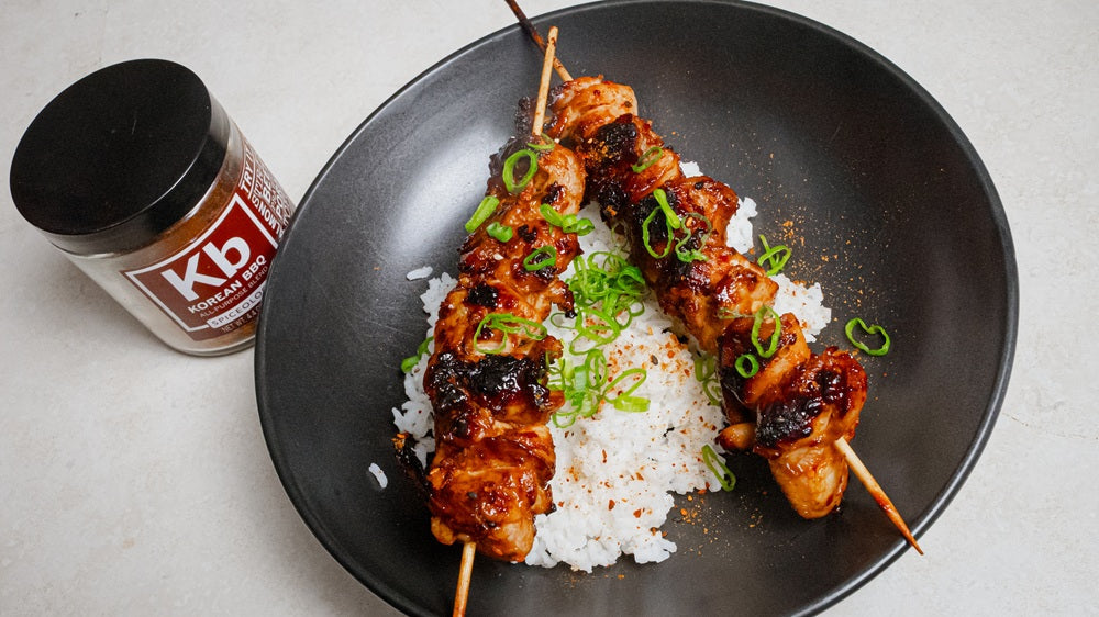 Plate of 2 chicken skewers over rice next to jar of Spiceology Korean BBQ seasoning