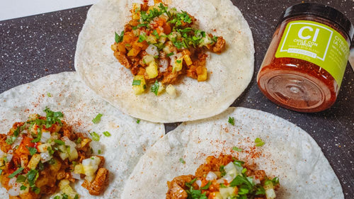 Three Loaded Chopped Pork Tacos next to a jar of Spiceology Chile con Limon seasoning