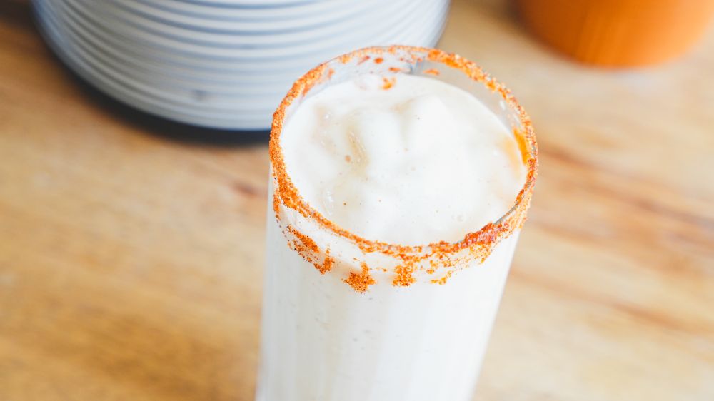 Glass filled with Frosted Peach Lemonade Milkshake and rimmed with Spiceology Smoky Honey Habanero seasoning