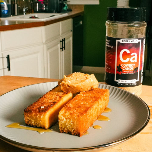 Plated Cornbread Sticks topped with Honey Butter next to a jar of Spiceology Cowboy Candy
