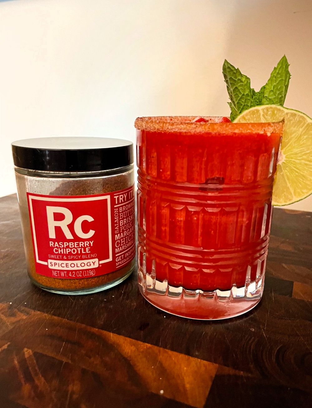 Glass with a margarita next to a jar of Spiceology's Raspberry Chipotle seasoning