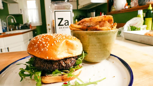 Plated Whipped Feta-Stuffed Za'atar Kafta Burger next to a jar of Spiceology Za'atar blend