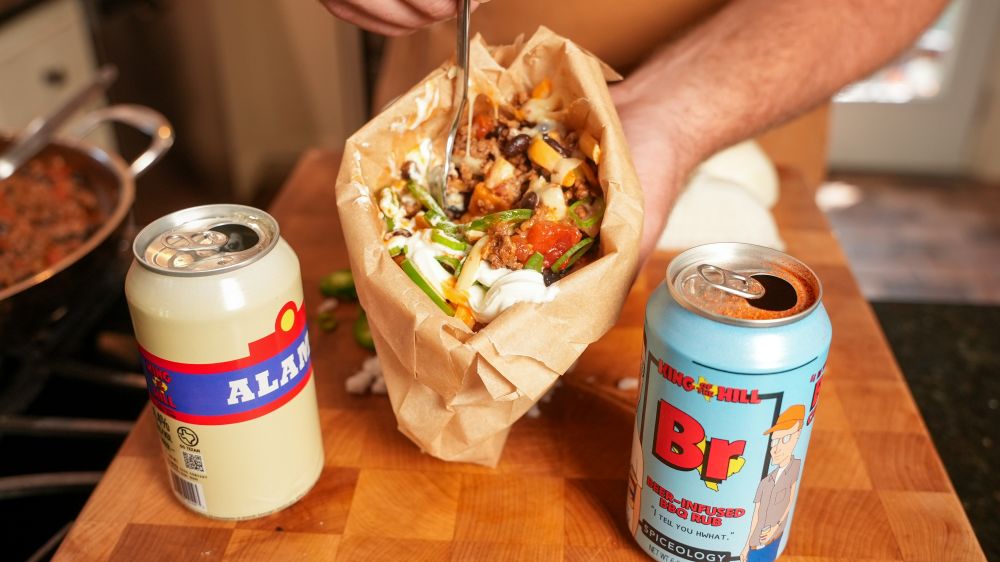 Finished Walking Taco next to a can of Spiceology X King of the Hill Beer-Infused BBQ Rub and can of Alamo Beer Co. 