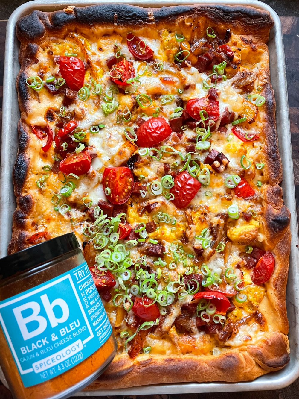 Finished Sheet Pan Breakfast Pizza with a jar of Spiceology Black & Bleu seasoning