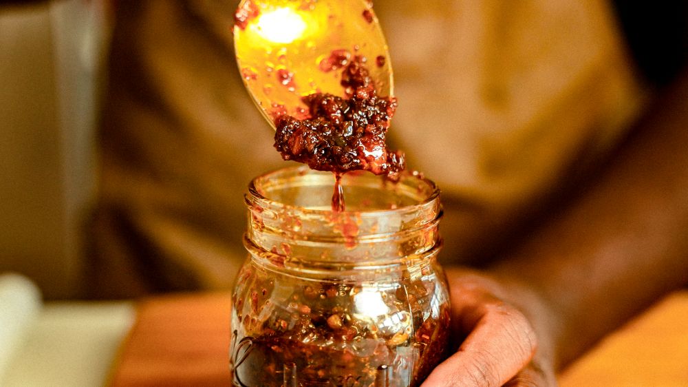 Spooning out the Black Magic XO Sauce from its jar.