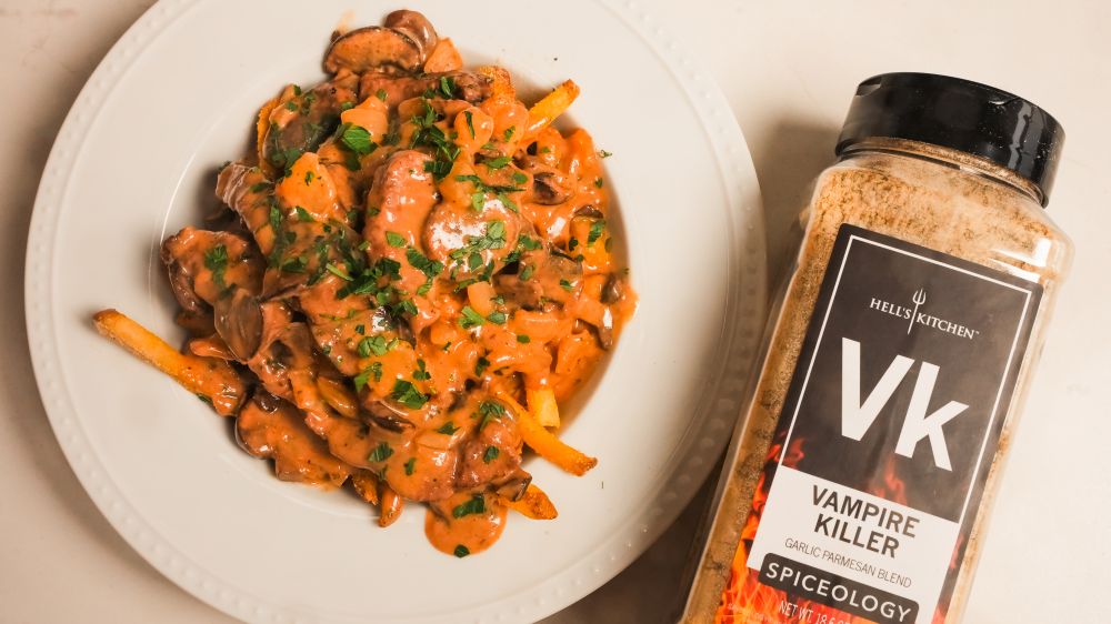 Plated Beef & Mushroom Stroganoff & Fries next to a bottle of Spiceology Vampire Killer seasoning