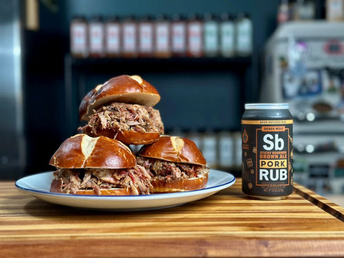 Plated and stacke Chicken-Style Pulled Pork on a pretzel bun next to a can of Sticky Bourbon Brown Ale Bourbon rub 