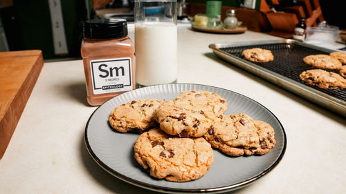 Plate of S'mores Brown Butter Chocolate Chip Cookies on plate next to a glass of milk and jar of Spiceology S'mores blend