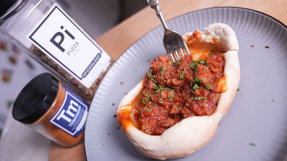 Plated Pizza Pot Pie next to jars of Spiceology Tomatador and Pizza blends