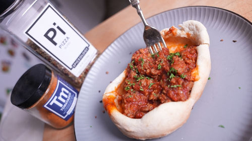 Plated Pizza Pot Pie next to jars of Spiceology Tomatador and Pizza blends