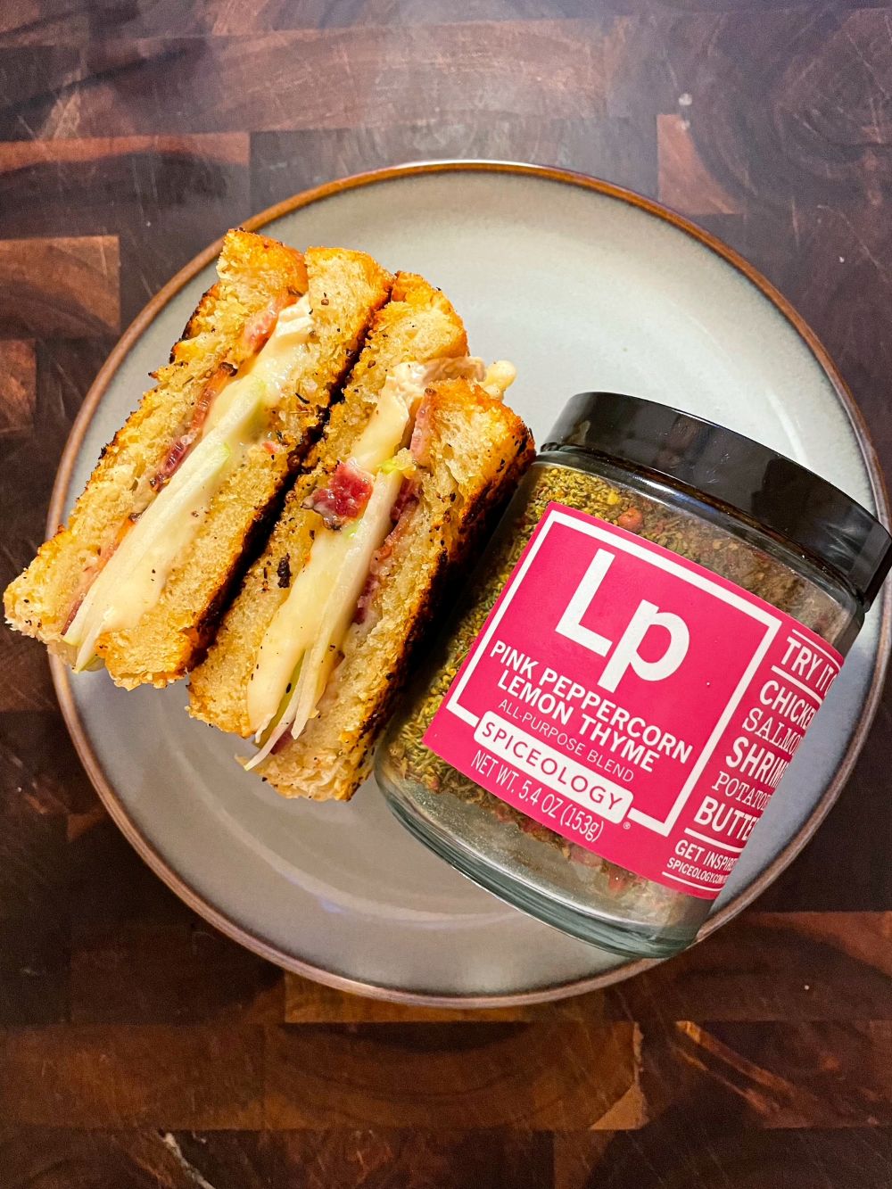 Plated Bacon, Brie & Apple Grilled Cheese next to a jar of Spiceology Pink Peppercorn Lemon Thyme blend