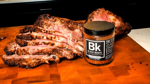 Sliced prime rib crusted with brown butter and Black Magic seasoning, served beside a jar of Spiceology Black Magic blend