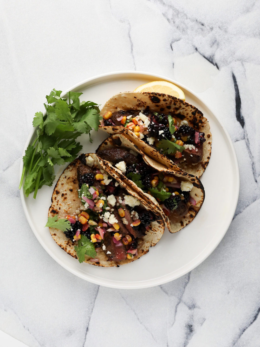 steak tacos with blackberry corn salsa on white background