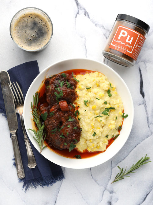 a white bowl with braised oxtail and polenta on a marble background