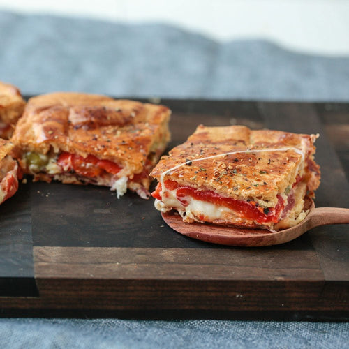 greek freak anitpasto bake squares on cutting board on serving spoon