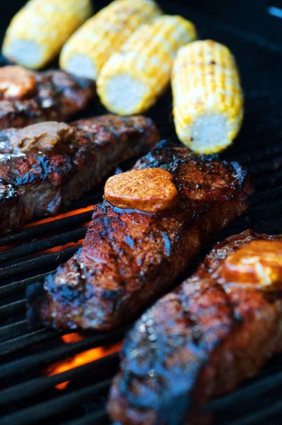 New York steak with corn on the cob on the grill