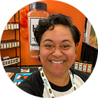 Circular cropped headshot of a smiling woman in a Spiceology store setting
