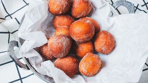 Basket of Apple Cinnamon Maple Cream Filled Donuts featuring Warm, fluffy donut holes filled with rich maple sweetness and finished with Spiceology's Apple Cinnamon seasoning on a white cloth with a blue and white checkered tablecloth.