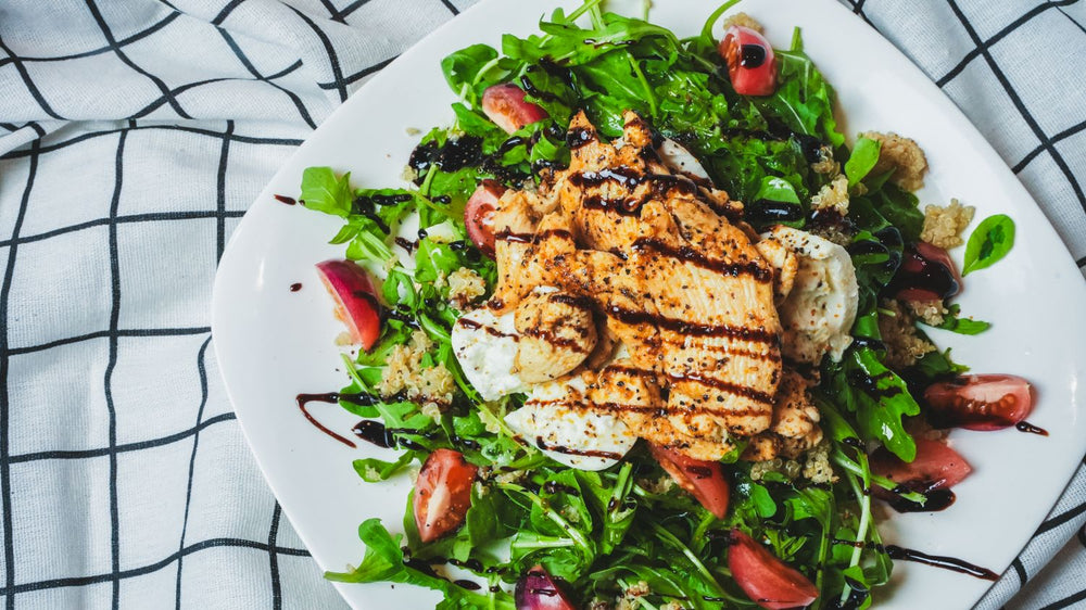 Overhead view of a salad with grilled protein slices on a white ceramic plate