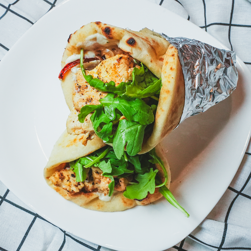 Close-up of a taco filled with grilled protein and fresh cilantro on a white plate