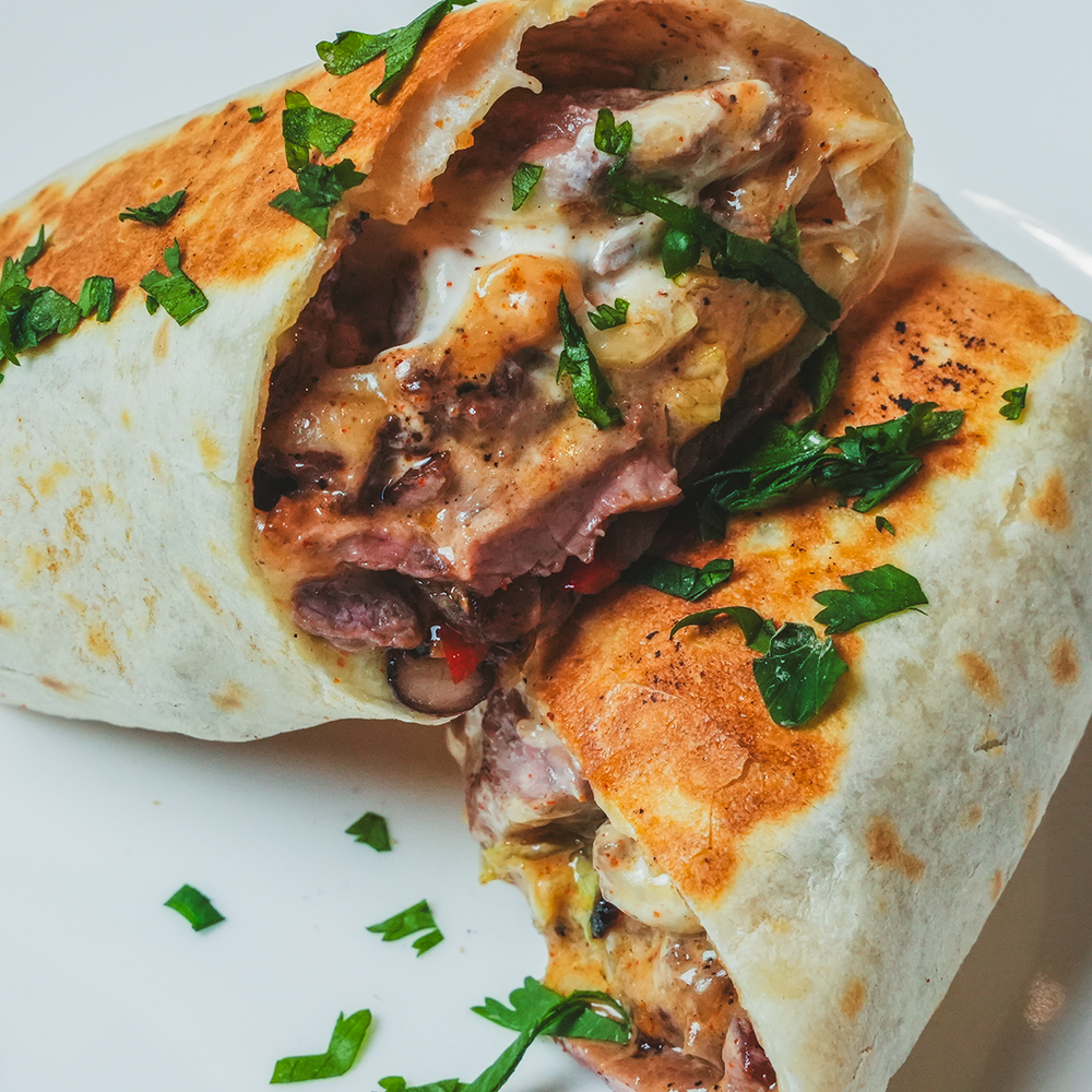 Close-up of a burrito or wrap cut open to reveal layered fillings
