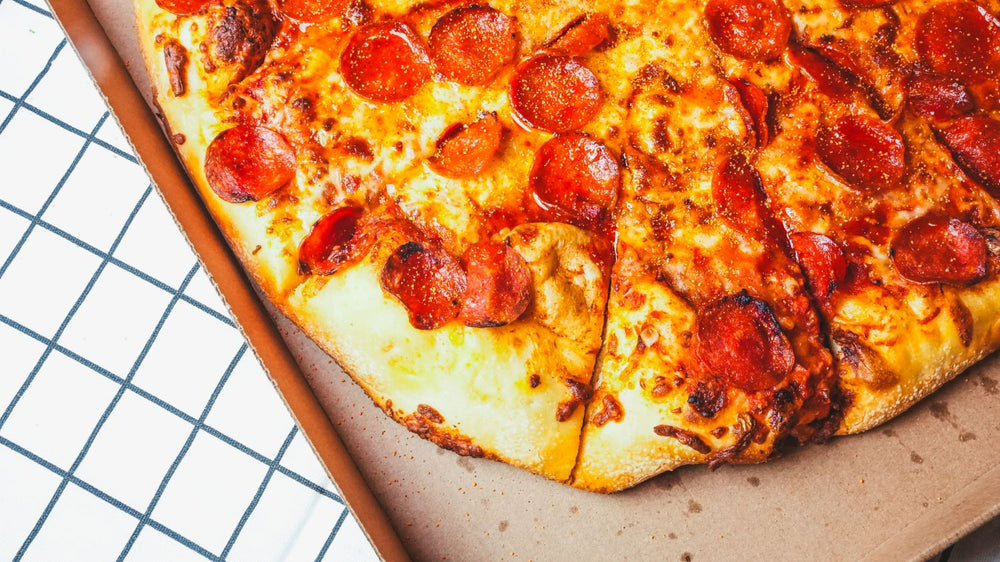 Overhead view of a loaded pepperoni pizza with crispy edges on a pizza stone