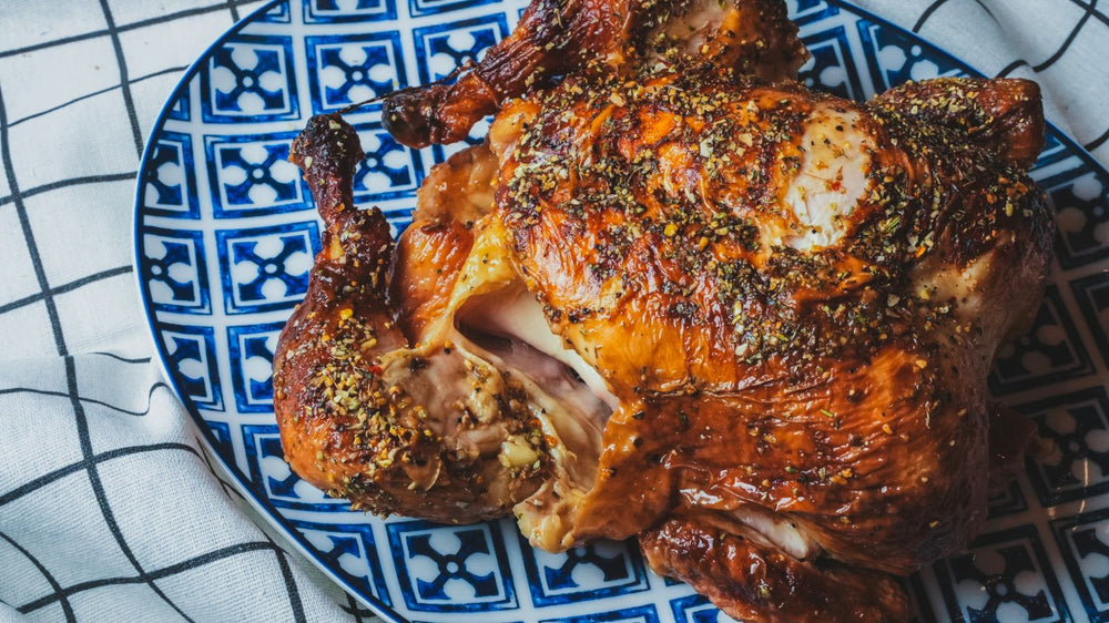 Whole roasted herb chicken on a blue and white patterned ceramic plate