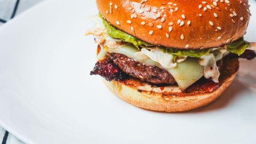 Close-up side view of a classic cheeseburger with a sesame seed bun