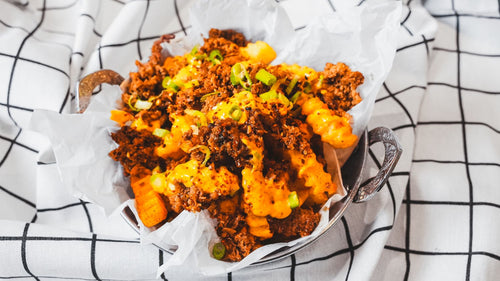 Overhead close-up of crispy fries with orange sauce and green onion garnish