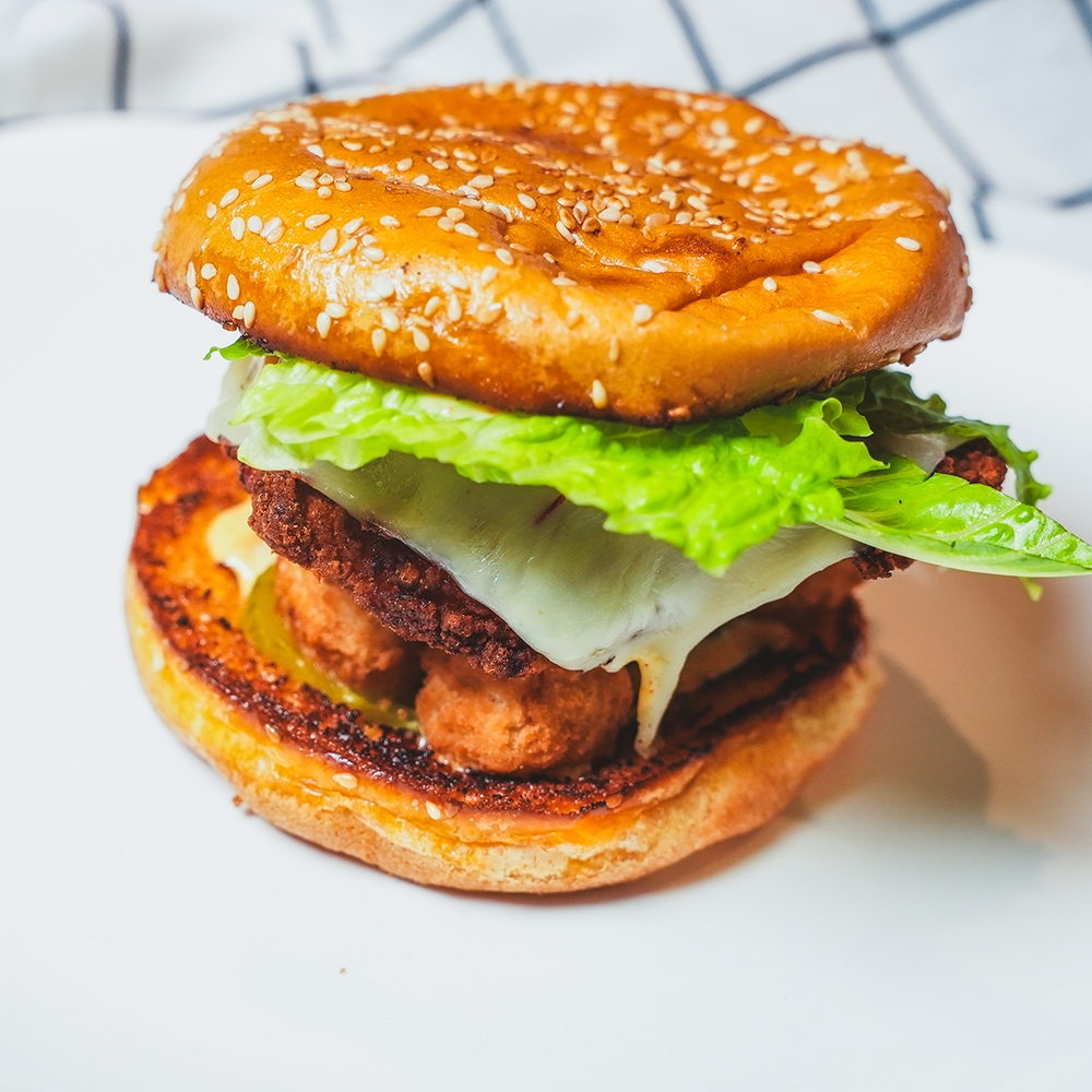 Burger with a grilled patty and lettuce on a white surface