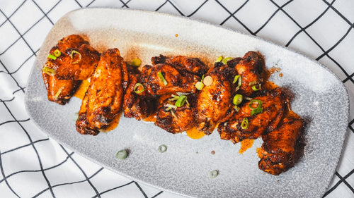 Overhead view of sauced chicken wings plated on a white dish