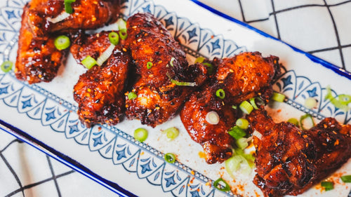 Glazed chicken wings arranged on a blue and white patterned ceramic plate