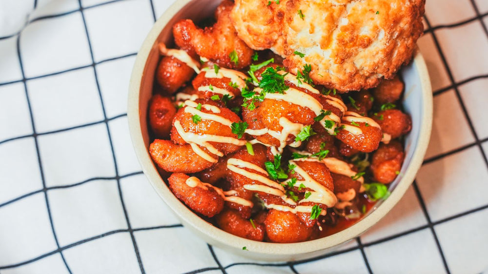 Bowl of roasted or glazed tomatoes with a cream drizzle on a white plate