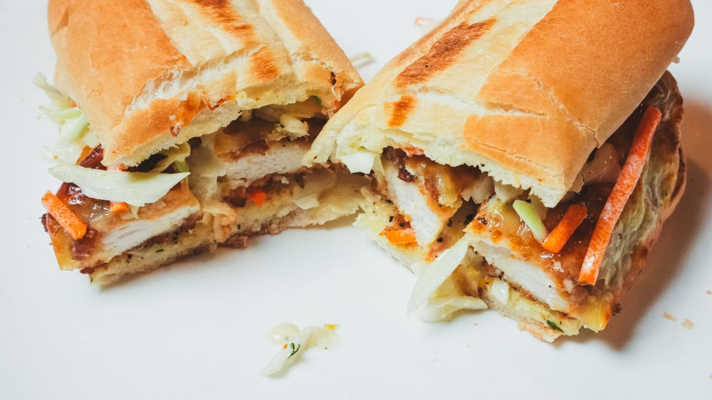 Sub sandwich cut in half and stacked to reveal layers of seasoned fillings, cheese, and vegetables
