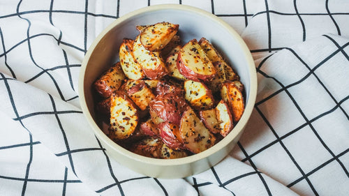 Overhead view of roasted potato wedges in a white ceramic bowl