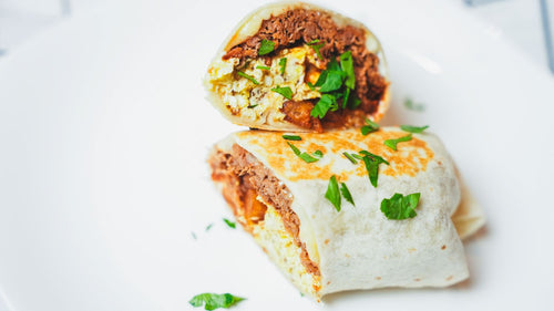 Close-up of a burrito cut in half revealing its filling on a white plate