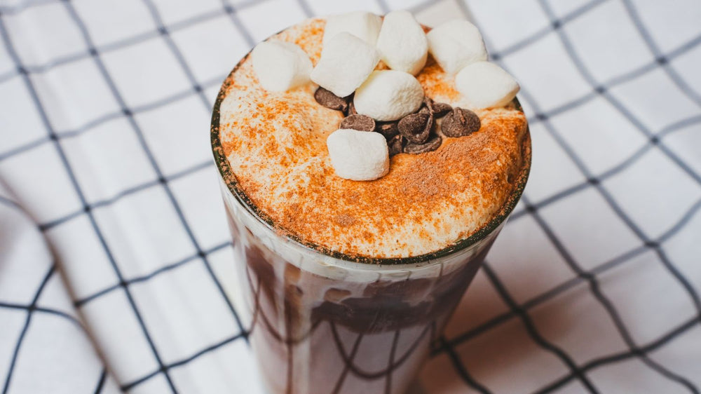 Hot chocolate with marshmallows and chocolate chips on a checkered tablecloth