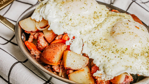 Salsa Verde Chorizo Skillet featuring a sizzling breakfast skillet of golden potatoes seasoned with Spiceology's Salsa Verde, tender peppers and onions, savory chorizo, and eggs, finished with another bright hit of zesty Salsa Verde on a checkered tablecloth