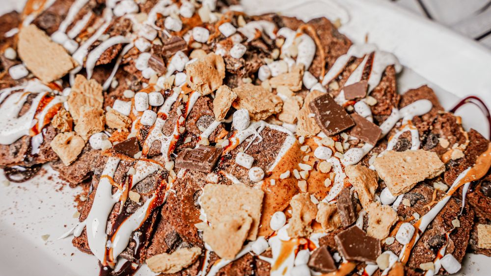Close-up of a dessert with graham crackers, chocolate, and marshmallows on a white plate.