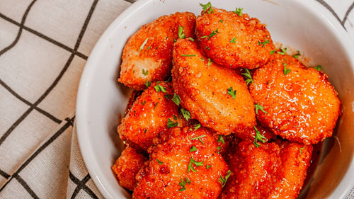 Smoky Honey Habanero Chicken Nuggets featuring Crispy fried chicken nuggets tossed in Spiceology's Smoky Honey Habanero seasoning for a glossy sweet-heat finish that balances smoky depth with chile warmth on a white plate with a checkered cloth background