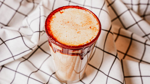 Glass of creamy beverage with a red rim on a checkered cloth